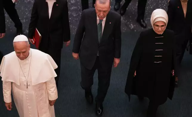 Pope Leo XIV, flanked by Turkish President Recep Tayyip Erdogan, center, and his wife Emine, leaves at the end of a meeting with authorities, members of the civil society and diplomats in the Presidential Palace's national library, in Ankara, Turkey, Thursday, Nov. 27, 2025. (AP Photo/Domenico Stinellis)