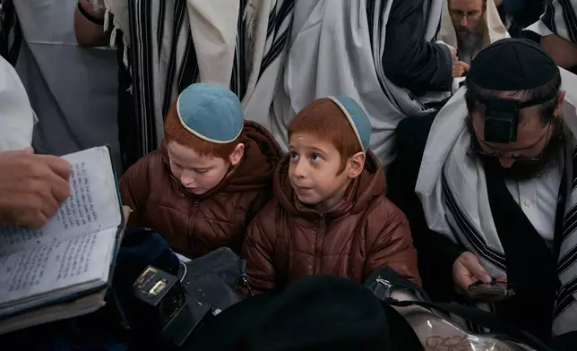 Children write letters as Chabad-Lubavitch rabbis gather in prayer at the resting place of the Rebbe, Rabbi Menachem M. Schneerson, one of Judaism’s most influential figures, in the Queens borough of New York on Friday, Nov. 14, 2025, during the International Conference of Chabad-Lubavitch Emissaries. (AP Photo/Andres Kudacki)