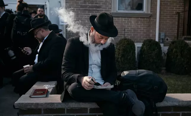 A Chabad-Lubavitch rabbi vapes as he prays near the resting place of the Rebbe, Rabbi Menachem M. Schneerson, one of Judaism’s most influential figures, in the Queens borough of New York on Friday, Nov. 14, 2025, during the International Conference of Chabad-Lubavitch Emissaries. (AP Photo/Andres Kudacki)