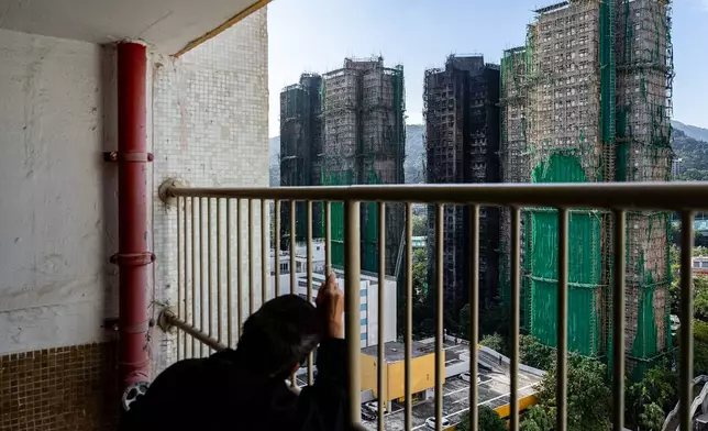 A resident looks at the burned buildings after deadly fires at Wang Fuk Court, a residential estate in the Tai Po district of Hong Kong's New Territories, Friday, Nov. 28, 2025. (AP Photo/Chan Long Hei)