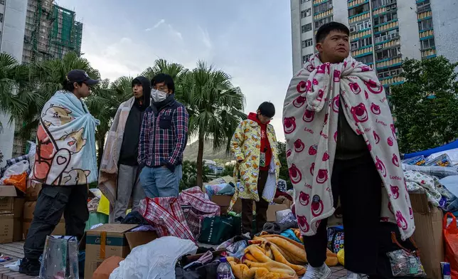 People stand amid donated supplies following the fire that started Wednesday at Wang Fuk Court, a residential estate in the Tai Po district of Hong Kong's New Territories, Friday, Nov. 28 2025. (AP Photo/Chan Long Hei)