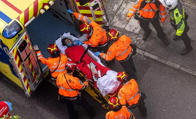 Health workers evacuate a woman from a fire which broke out at Wang Fuk Court, a residential estate in the Tai Po district of Hong Kong's New Territories, Thursday, Nov. 27, 2025. (AP Photo/Chan Long Hei)