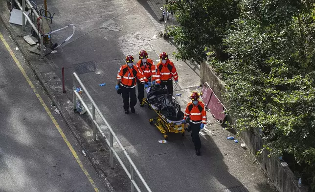 Health workers remove a body after a deadly fire Wednesday at Wang Fuk Court, a residential estate in the Tai Po district of Hong Kong's New Territories, Friday, Nov. 28, 2025. (AP Photo/Chan Long Hei)