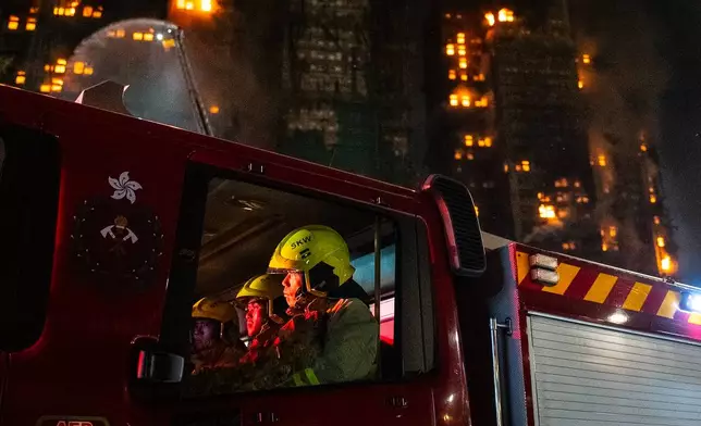 Firefighters rest at the fire truck after a fire broke out at Wang Fuk Court, a residential estate in the Tai Po district of Hong Kong's New Territories, Wednesday, Nov. 26 2025. (AP Photo/Chan Long Hei)