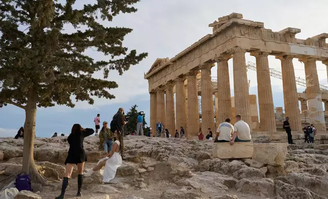 Tourists visit the 5th century B.C. Parthenon temple atop the Acropolis hill in Athens, Friday, Oct. 31, 2025. (AP Photo/Petros Giannakouris)
