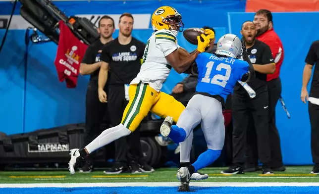 Green Bay Packers wide receiver Dontayvion Wicks (13) makes a catch in front of Detroit Lions safety Thomas Harper (12) for a touchdown during the first half an NFL football game in Detroit, Thursday, Nov. 27, 2025. (AP Photo/Paul Sancya)