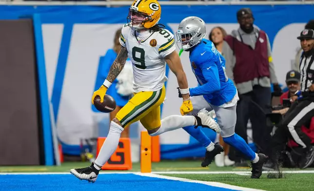 Green Bay Packers wide receiver Christian Watson (9) runs in for a touchdown on front of Detroit Lions cornerback Amik Robertson (21) during the second half an NFL football game in Detroit, Thursday, Nov. 27, 2025. (AP Photo/Ryan Sun)