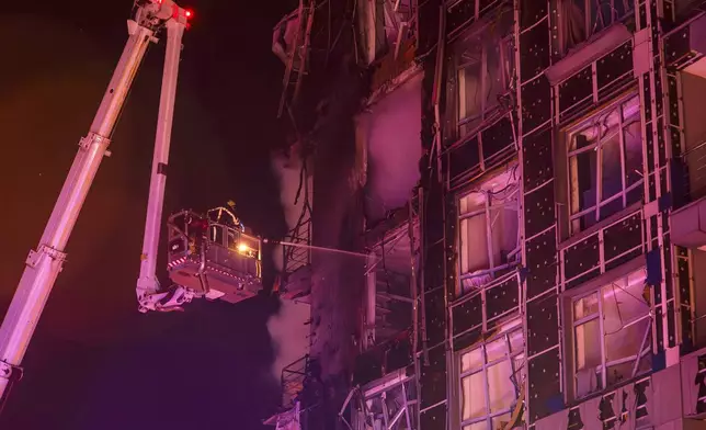 Emergency services personnel work to extinguish a fire following a Russian attack in Kyiv, Ukraine, Tuesday, Nov. 25, 2025. (AP Photo/Dan Bashakov)