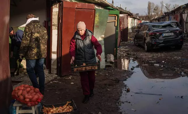 A woman collects salvaged food from her garage damaged after a Russian strike on Kyiv, Ukraine, on Tuesday, Nov. 25, 2025. (AP Photo/Evgeniy Maloletka)