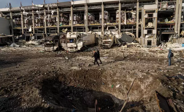 Police officers walk near a crater in front of a Novus logistics center damaged after a Russian strike on Kyiv, Ukraine, on Tuesday, Nov. 25, 2025. (AP Photo/Evgeniy Maloletka)