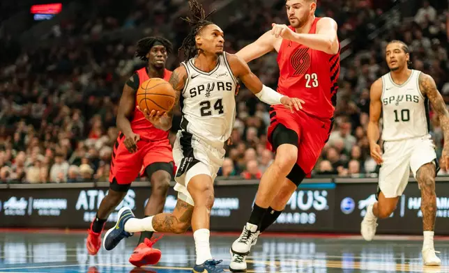San Antonio Spurs guard/forward Devin Vassell (24) drives to the basket past Portland Trail Blazers center Donovan Clingan (23) during the first half of an Emirates NBA Cup basketball game, Wednesday, Nov. 26, 2025, in Portland, Ore. (AP Photo/Ali Gradischer)
