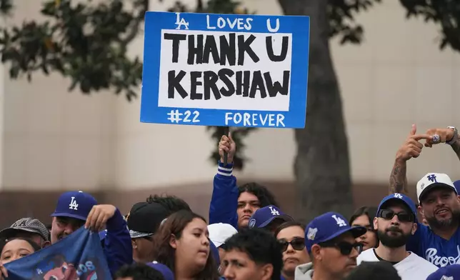 Fans holds signs along the route before a parade to celebrate the Los Angeles Dodgers baseball team's World Series win on Monday, Nov. 3, 2025, in Los Angeles. (AP Photo/Jae C. Hong)