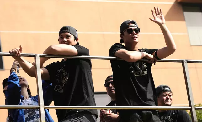 Los Angels Dodgers' Shohei Ohtani, left, and Yoshinobu Yamamoto wave from a double-decker bus during a parade to celebrate the baseball team's World Series win on Monday, Nov. 3, 2025, in Los Angeles. (AP Photo/Jae C. Hong)