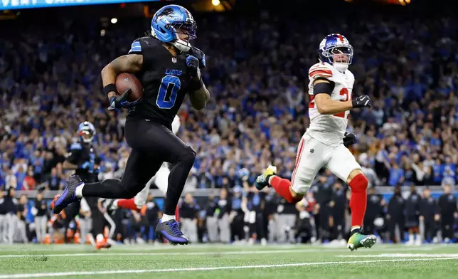 Detroit Lions running back Jahmyr Gibbs (0) runs past New York Giants safety Dane Belton (24) for a touchdown in overtime of an NFL football game in Detroit, Sunday, Nov. 23, 2025. (AP Photo/Rey Del Rio)