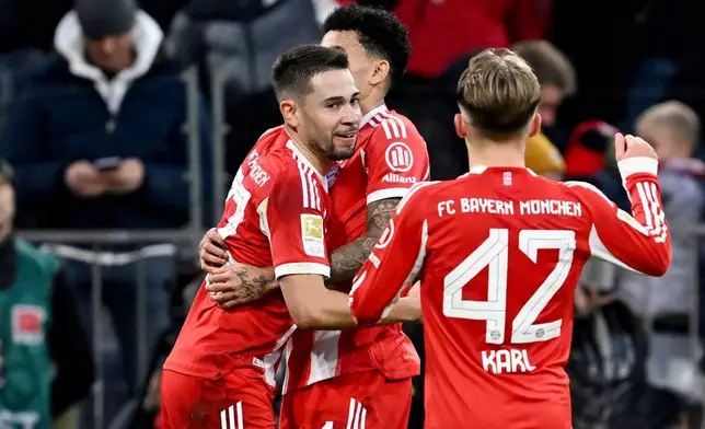 Bayern Munich's Raphaël Guerreiro, left, celebrates scoring during the Bundesliga soccer match between Bayern Munich and FC St. Pauli in Munich, Germany, Saturday Nov. 29, 2025. (Sven Hoppe/dpa via AP)