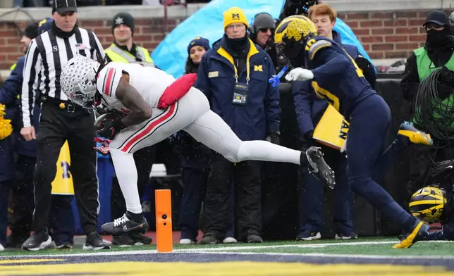 Ohio State wide receiver Jeremiah Smith, left, catches a pass for a touchdown against Michigan defensive back Zeke Berry during the first half of an NCAA college football game, Saturday, Nov. 29, 2025, in Ann Arbor, Mich. (AP Photo/Ryan Sun)