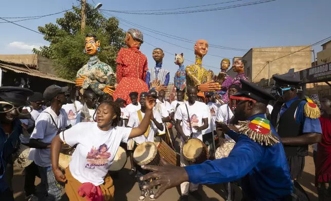 Dancers perform as giant marionettes parade through the streets during an art festival in Bamako, Mali, on Nov. 6, 2025. (AP Photo/Moustapha Diallo)