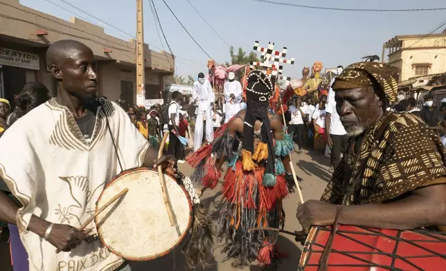 A dancer performs as giant marionettes parade through the streets during an art festival in Bamako, Mali, on Nov. 6, 2025. (AP Photo/Moustapha Diallo)