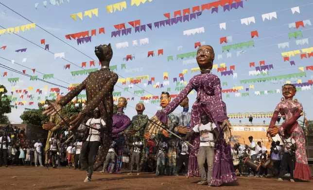 Performers carry giant marionettes during an art festival in Bamako, Mali, on Nov. 6, 2025. (AP Photo/Moustapha Diallo)