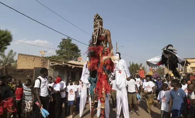 Performers on stilts parade through the streets during an art festival in Bamako, Mali, on Nov. 6, 2025. (AP Photo/Moustapha Diallo)