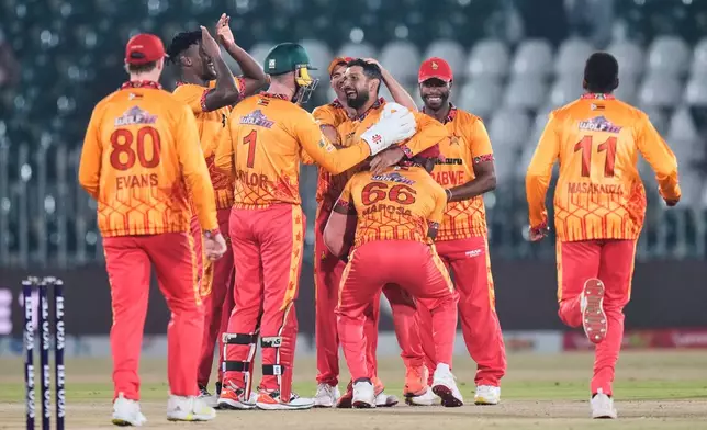 Zimbabwe's Sikandar Raza, center, celebrates with teammates after the dismissal of Sri Lanka's Kamindu Mendis during the tri-series T20 cricket match between Sri Lanka and Zimbabwe, in Rawalpindi, Pakistan, Thursday, Nov. 20, 2025. (AP Photo/Anjum Naveed)
