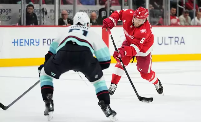 Detroit Red Wings defenseman Ben Chiarot, right, shoots against Seattle Kraken center Shane Wright during the second period of an NHL hockey game, Tuesday, Nov. 18, 2025, in Detroit. (AP Photo/Ryan Sun)