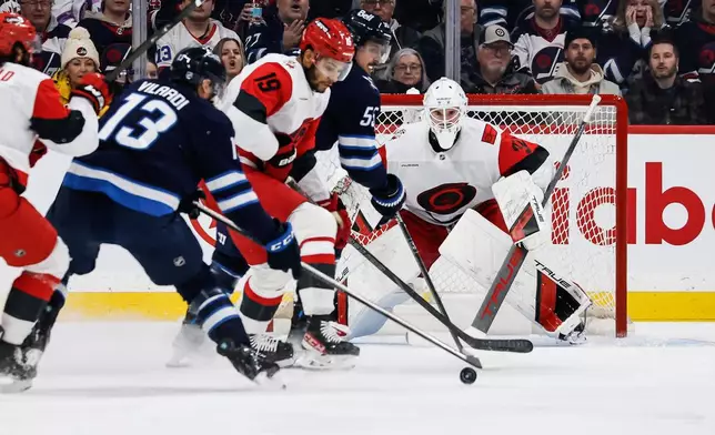 Carolina Hurricanes' K'Andre Miller (19) defends against Winnipeg Jets' Gabriel Vilardi (13) and Mark Scheifele (55) during first-period NHL hockey game action in Winnipeg, Manitoba, Friday, Nov. 21, 2025. (John Woods/The Canadian Press via AP)