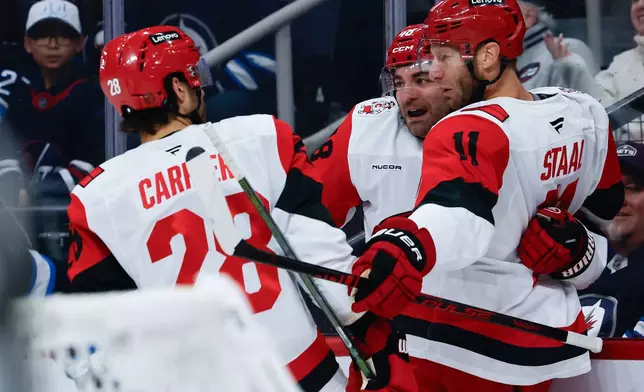 Carolina Hurricanes' William Carrier (28), Jordan Staal (11) and Jordan Martinook (48) celebrate after Staal's goal against the Winnipeg Jets during first-period NHL hockey game action in Winnipeg, Manitoba, Friday, Nov. 21, 2025. (John Woods/The Canadian Press via AP)