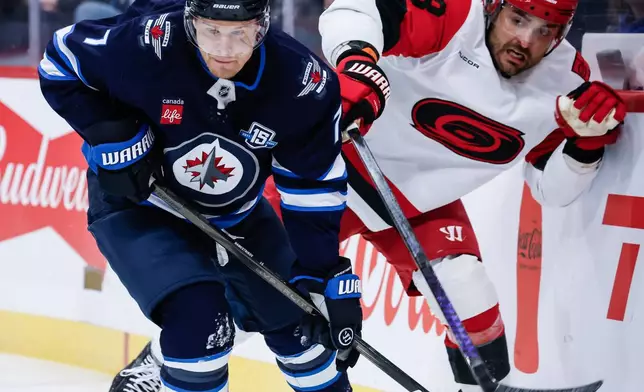 Winnipeg Jets' Vladislav Namestnikov (7) and Carolina Hurricanes' William Carrier (28) battle along the boards during first-period NHL hockey game action in Winnipeg, Manitoba, Friday, Nov. 21, 2025. (John Woods/The Canadian Press via AP)