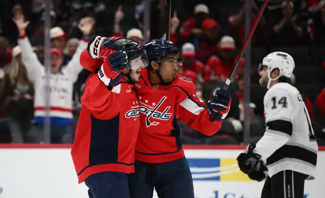 Washington Capitals defenseman Matt Roy, left, celebrates after his goal with right wing Justin Sourdif, center, near Los Angeles Kings right wing Alex Laferriere (14) during the first period of an NHL hockey game, Monday, Nov. 17, 2025, in Washington. (AP Photo/Nick Wass)