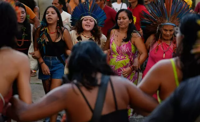 Indigenous peoples sing and dance as they participate in an opening ceremony as part of the People's Summit offsite from the COP30 U.N. Climate Summit, Wednesday, Nov. 12, 2025, in Belem, Brazil. (AP Photo/Fernando Llano)