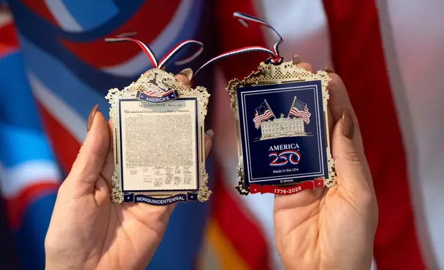 Jennifer Condon, Executive Vice President of America250, displays the front and back of a commemorative ornament released by America250 as part of events leading up to the 250th anniversary of the signing of the Declaration of Independence in 1776, Thursday, Nov. 13, 2025, in Washington. (AP Photo/Mark Schiefelbein)