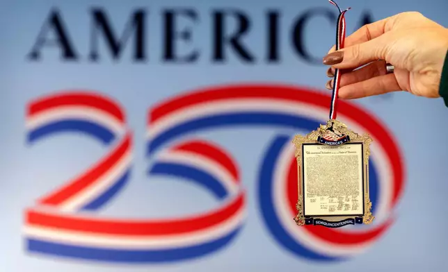 Jennifer Condon, Executive Vice President of America250, displays the front of a commemorative ornament released by America250 as part of events leading up to the 250th anniversary of the signing of the Declaration of Independence in 1776, is photographed Thursday, Nov. 13, 2025, in Washington. (AP Photo/Mark Schiefelbein)