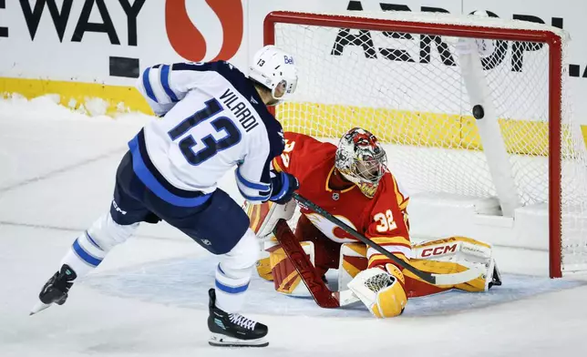 Winnipeg Jets' Gabriel Vilardi (13) scores the winning goal on Calgary Flames goalie Dustin Wolf during a shootout in overtime in an NHL hockey game in Calgary, Alberta, Saturday, Nov. 15, 2025. (Jeff McIntosh/The Canadian Press via AP)
