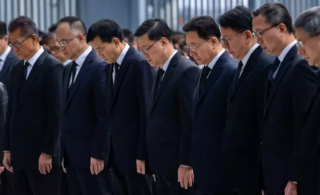 Hong Kong Chief Executive John lee, center and other officers observe a moment of silence for the victims of the deadly fire that started Wednesday at Wang Fuk Court, a residential estate in the Tai Po district of Hong Kong's New Territories, Saturday, Nov. 29, 2025. (AP Photo/Chan Long Hei)