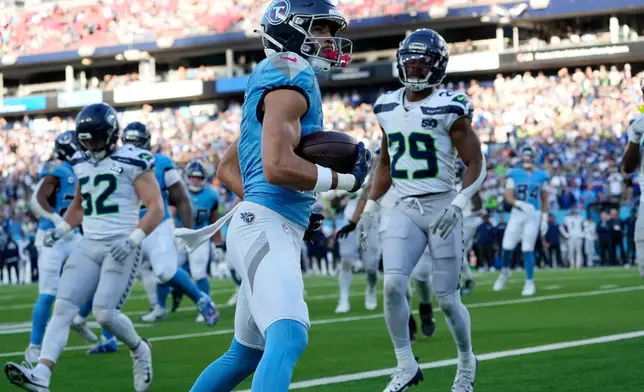 Tennessee Titans wide receiver Chimere Dike, center, scores a touchdown against the Seattle Seahawks during the second half of an NFL football game Sunday, Nov. 23, 2025, in Nashville, Tenn. (AP Photo/George Walker IV)