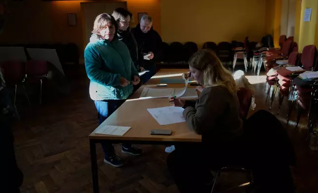 Voters register at a polling station during the referendum on assisted dying for terminally ill patients, in Domzale, Slovenia, Sunday, Nov. 23, 2025. (AP Photo/Darko Bandic)