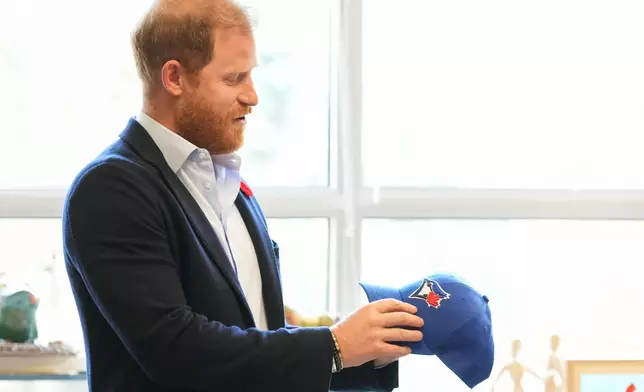 Prince Harry received a Toronto Blue Jays hat as he meets with some of Canada's oldest veterans, joining them in a creative arts program at Sunnybrook Hospital's veterans center in Toronto, Thursday, Nov. 6, 2025. (Nathan Denette /The Canadian Press via AP)