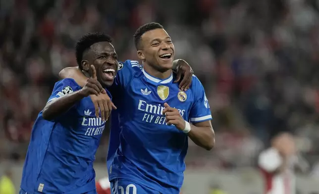 Real Madrid's Kylian Mbappe, right, celebrates with his teammate Vinicius Junior after scoring his side's fourth goal during the Champions League opening phase soccer match between Olympiacos and Real Madrid, in in Piraeus port, near Athens, Greece, Wednesday, Nov. 26, 2025. (AP Photo/Petros Giannakouris)