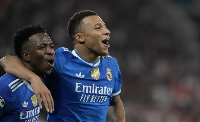 Real Madrid's Kylian Mbappe, right, celebrates with his teammate Vinicius Junior after scoring his side's fourth goal during the Champions League opening phase soccer match between Olympiacos and Real Madrid, in in Piraeus port, near Athens, Greece, Wednesday, Nov. 26, 2025. (AP Photo/Petros Giannakouris)