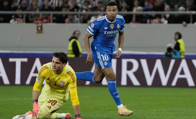Real Madrid's Kylian Mbappe, top, goes for the ball past Olympiacos' goalkeeper Konstantinos Tzolakis after scoring his side's opening goal during the Champions League opening phase soccer match between Olympiacos and Real Madrid in Piraeus port, near Athens, Greece, Wednesday, Nov. 26, 2025. (AP Photo/Thanassis Stavrakis)