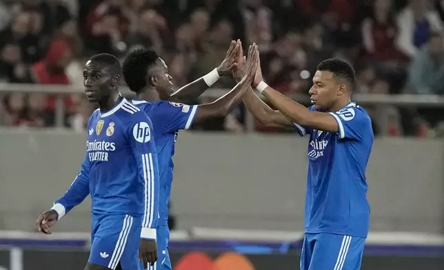 Real Madrid's Vinicius Junior, centre, celebrates with his teammate Kylian Mbappe, right, after scoring his side's fourth goal during the Champions League opening phase soccer match between Olympiacos and Real Madrid, in in Piraeus port, near Athens, Greece, Wednesday, Nov. 26, 2025. (AP Photo/Petros Giannakouris)