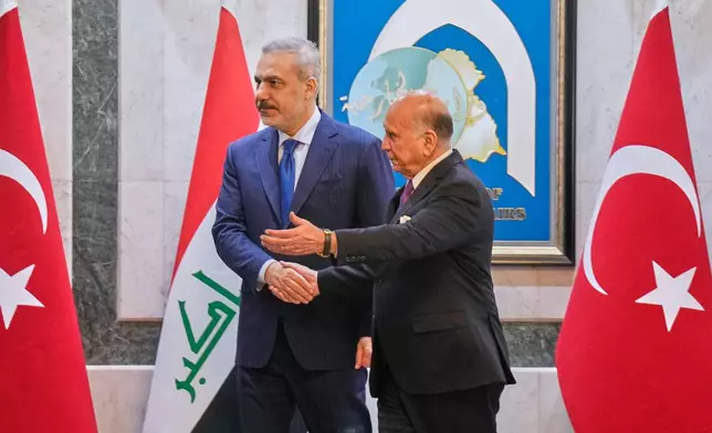 Iraqi Foreign Minister Fuad Hussein, right, shakes hands with Turkish Foreign Minister Hakan Fidan, in Baghdad, Iraq, Sunday, Nov. 2, 2025. (AP Photo/Hadi Mizban)