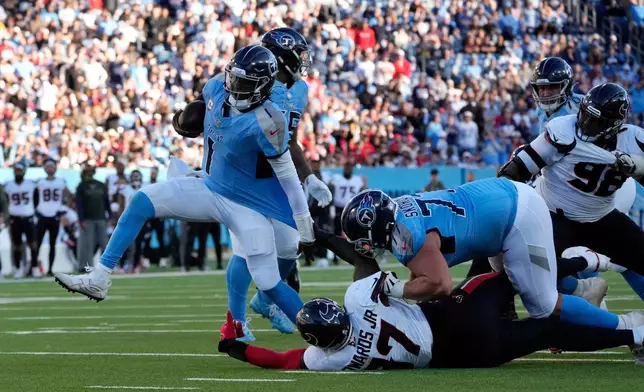 Tennessee Titans quarterback Cam Ward (1) is grabbed by Houston Texans defensive tackle Mario Edwards Jr. (97) during the second half of an NFL football game on Sunday, Nov. 16, 2025, in Nashville, Tenn. (AP Photo/George Walker IV)
