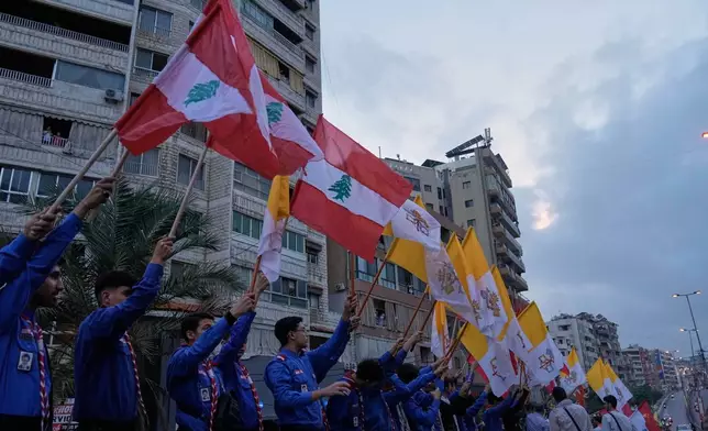 People wave Lebanese and Vatican flags as they wait to welcome Pope Leo XIV upon his arrival to Beirut, Lebanon, Sunday, Nov. 30, 2025. (AP Photo/Bilal Hussein)