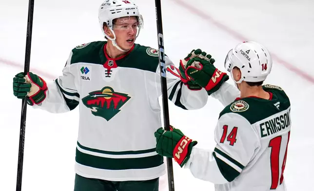 Minnesota Wild's Matt Boldy, left, celebrates with Joel Eriksson (14) after scoring during the first period of an NHL hockey game against the Pittsburgh Penguins in Pittsburgh, Friday, Nov. 21, 2025. (AP Photo/Gene J. Puskar)
