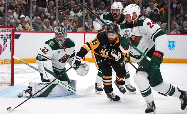 Pittsburgh Penguins' Tommy Novak (18) reaches for a rebound off Minnesota Wild goaltender Filip Gustavsson (32) with Zach Bogosian (24) defending during the second period of an NHL hockey game in Pittsburgh, Friday, Nov. 21, 2025. (AP Photo/Gene J. Puskar)