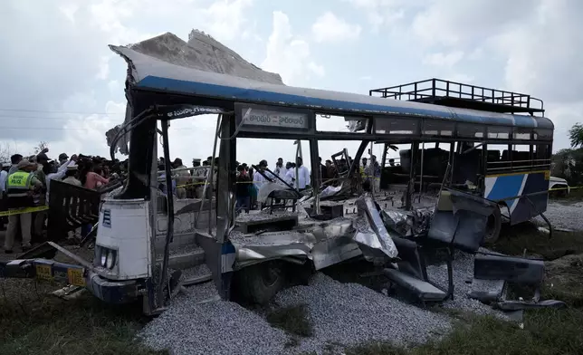 CAPTION CORRECTS THE LOCATION - People stand next to the passenger bus after a truck loaded with concrete stone chips rammed into it at Chevella in southern state of Telangana, India, Monday, Nov. 3, 2025. (AP Photo/Mahesh Kumar A.)