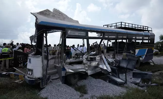 People stand next to the passenger bus after a truck loaded with concrete stone chips rammed into it at Chevalla in southern state of Telangana, India, Monday, Nov. 3, 2025. (AP Photo/Mahesh Kumar A.)