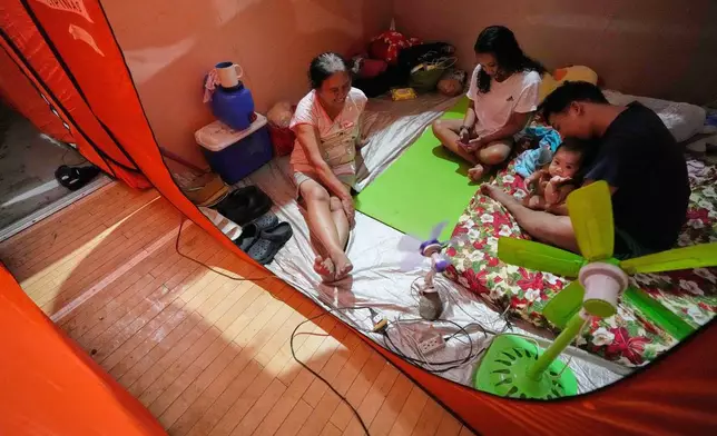 Judie Delector, right, and his family stay inside a tent at an evacuation center as Typhoon Fung-wong enters the country on Sunday, Nov. 9, 2025 in Quezon city, Philippines. (AP Photo/Aaron Favila)